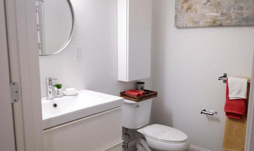 A white bathroom with a toilet, sink, and mirror.