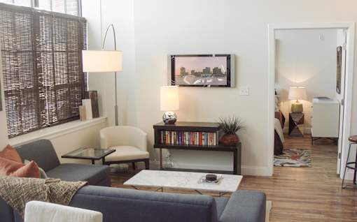 A living room with a grey couch and a painting on the wall.