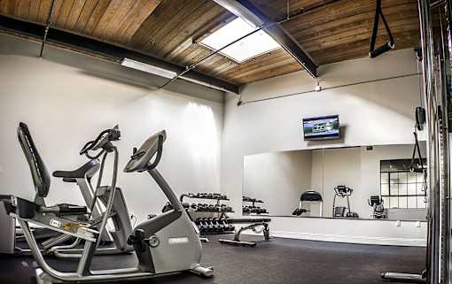 A gym with a wooden ceiling and a television mounted on the wall.