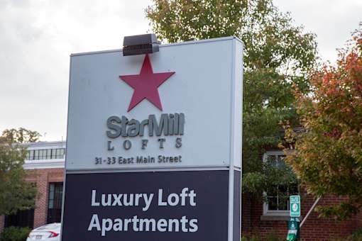 A sign for Starville Lofts is displayed in front of a tree.
