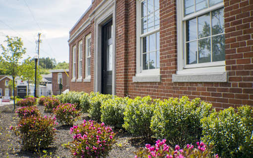 A red brick building with a flower bed in front.
