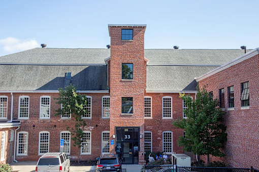 A red brick building with a black door and a black fence.