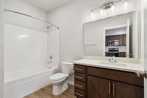 A white toilet is in a bathroom with a white tub and a white sink.