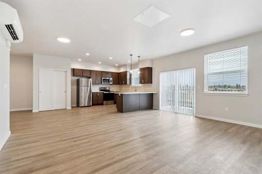 A spacious kitchen with wooden floors and white walls.