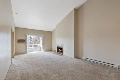 A large, empty room with a fireplace and a window.