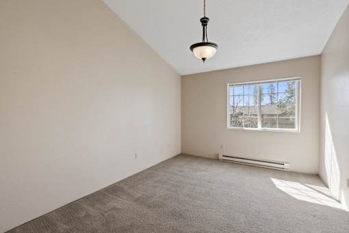 Empty room with a window and a hanging light fixture.
