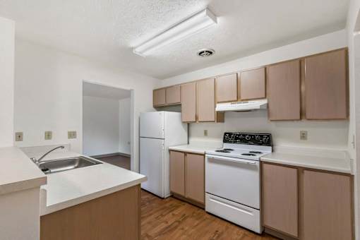 A kitchen with white appliances and brown cabinets.