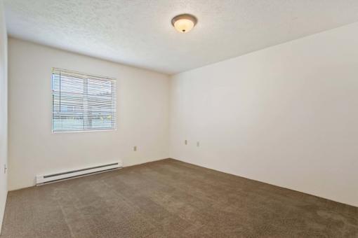 A room with a window and a heater on the floor.
