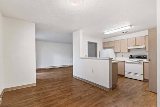 A kitchen with white appliances and wooden floors.