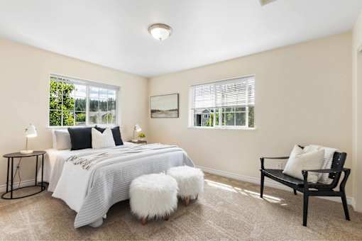 A bedroom with a large bed, a bench, and a window.