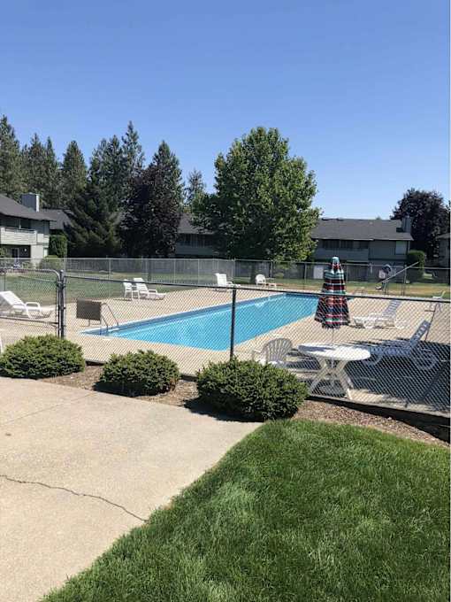A pool surrounded by a fence and chairs.