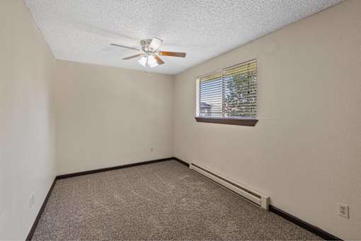 A room with a ceiling fan and a window with blinds.