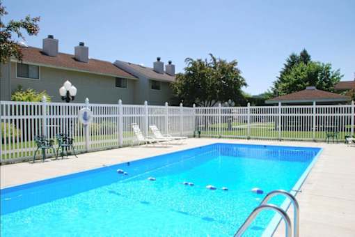 A pool surrounded by a fence and chairs.