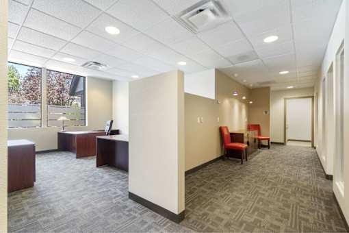 A carpeted hallway with a desk and chairs.