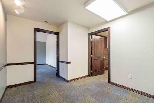 A hallway with a carpeted floor and two doors, one of which is open.