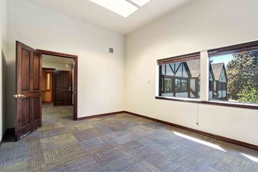 A room with a carpeted floor, a window, and a door.