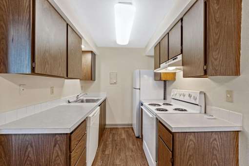A kitchen with white appliances and wooden cabinets.