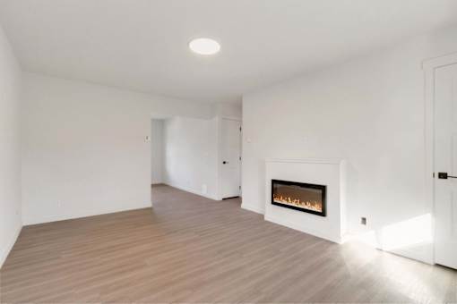 A white room with a fireplace and wooden flooring.
