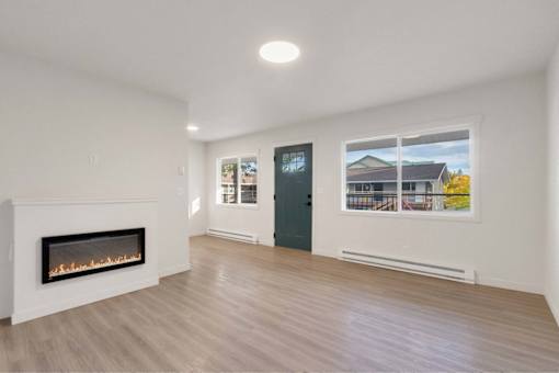 A room with a fireplace and a window showing a view of a house.
