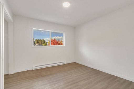 A room with a window and a picture of a forest on the wall.