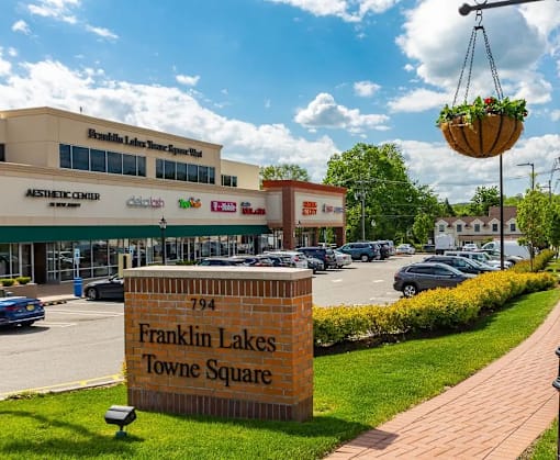A sign for Franklin Lakes Towne Square stands in front of a building.