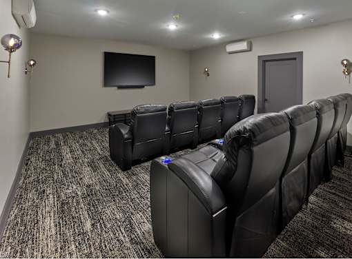 A row of black leather seats in a movie theater.