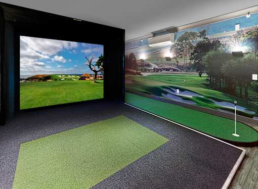 A room with a golf simulator and a large screen showing a golf course.