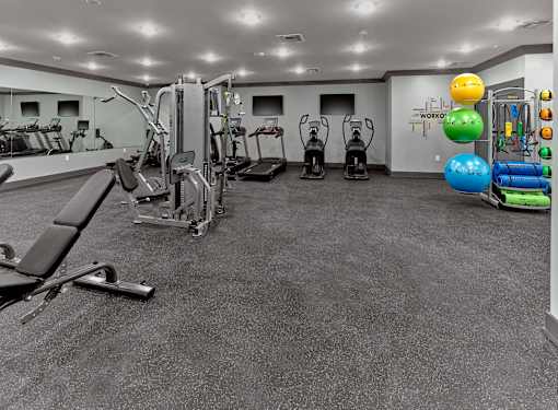 A gym with a variety of equipment including treadmills, weights, and exercise balls.