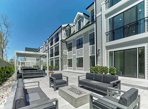 A modern outdoor seating area with black couches and tables in front of a building.