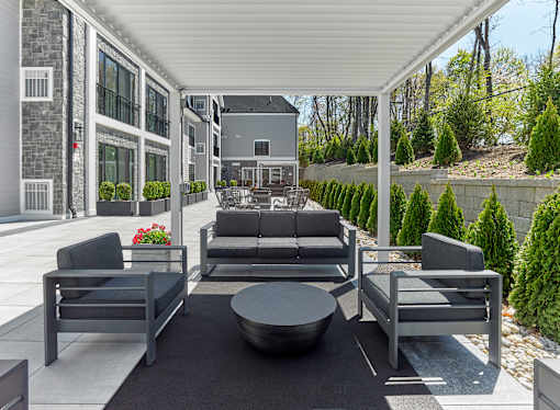 A patio with grey furniture and a black rug.