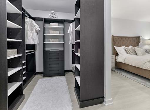A bedroom with a large bed and a walk-in closet with shelves.