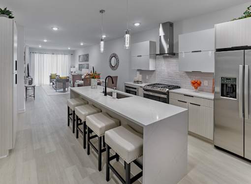 A modern kitchen with a long white island and stainless steel appliances.