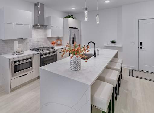 A modern kitchen with a white marble island and stainless steel appliances.