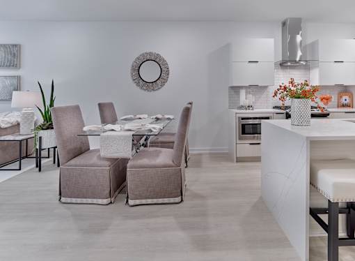 A modern dining room with a white table and grey chairs.