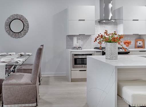 A modern kitchen with a grey chair and a white island.