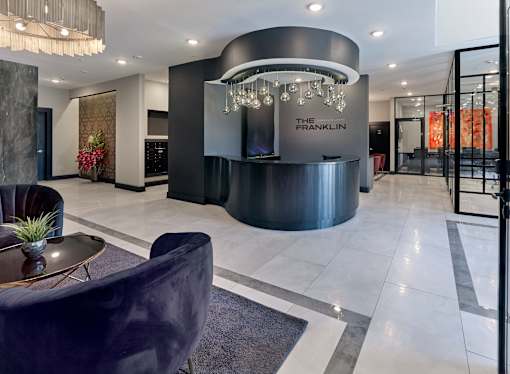 A modern lobby with a reception desk and a chandelier.