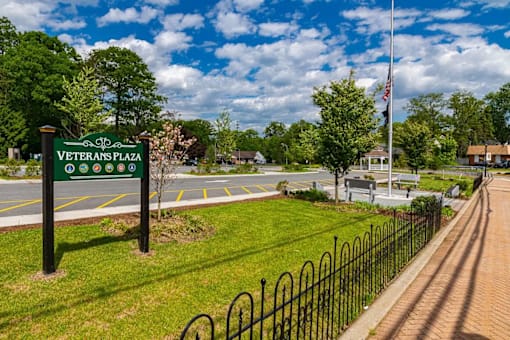 A sign that says Veterans Plaza stands in front of a grassy area.