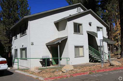 A white house with a green door and a sign on the front.