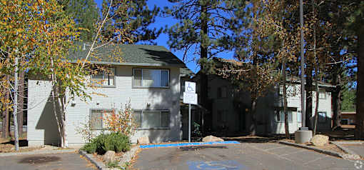 A white building with a green roof is surrounded by trees.
