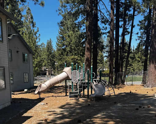 A playground with a slide and swings in a residential area.