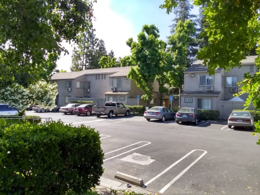 Colonial Farms Apartments - parking lot in front with apartment buildings in the background, trees