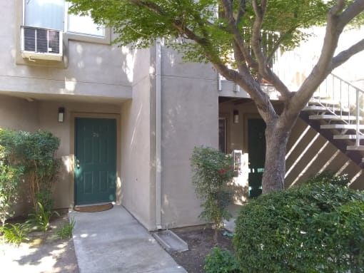 Colonial Farms Apartments - ground floor apartment entrance with concrete walkway up to door, with trees and bushes