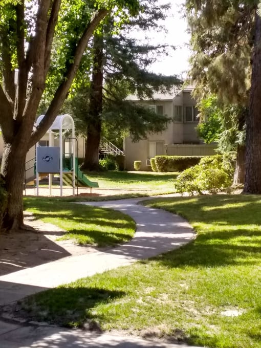 Colonial Farms Apartments - concrete walkway with grass and trees on either side