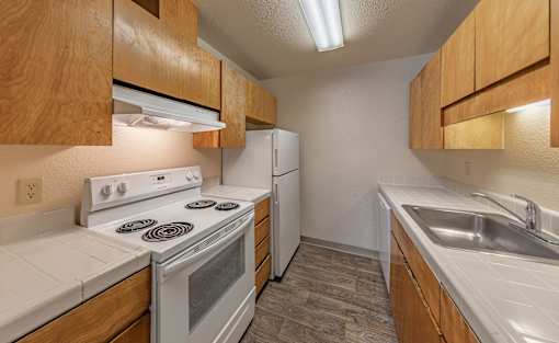 A kitchen with a stove, refrigerator, and sink.