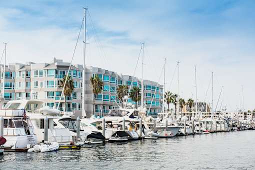 A marina with boats docked in front of a row of buildings.