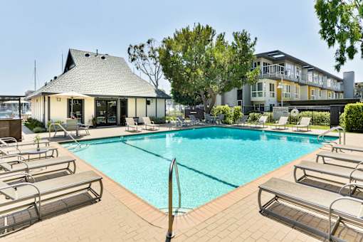 A pool with sun loungers and a building in the background.