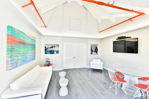 A living room with white furniture and a painting on the wall.