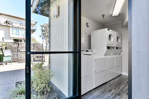 A modern kitchen with white appliances and a black door.