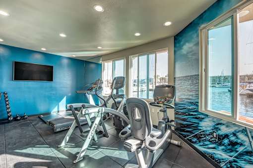 A gym with exercise equipment and a television on the wall.