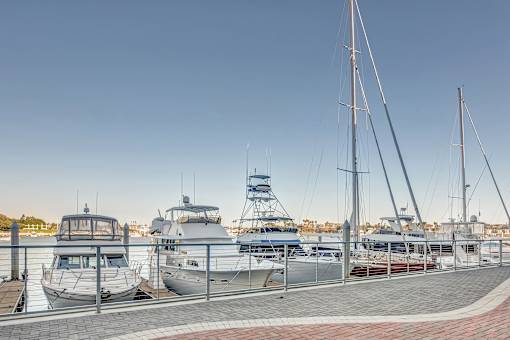 A row of boats are docked at a marina.